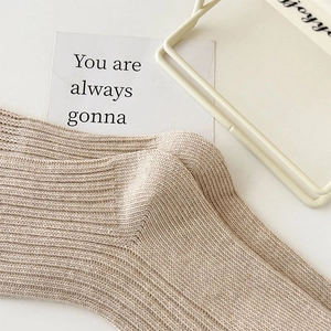 Macro detail of the soft vertical rib knit texture on the beige slouch socks