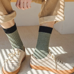 Detailed close-up of wool-blend ribbed socks in olive green and black on feet