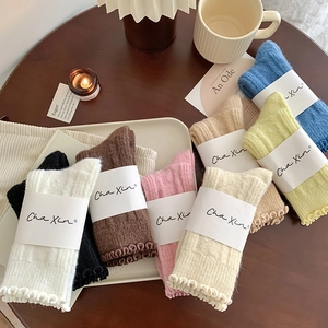 Close-up of cozy wool socks with ruffled cuffs arranged on a wooden table in warm light