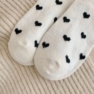 Close-up of white knitted socks with black heart pattern and fine texture detail