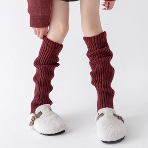 Detailed texture of wine red rib-knit leg warmers worn with plush white slippers