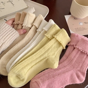 Detail of ruffled cuffs on thick wool socks in various warm colors for women
