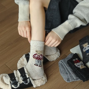 Detail of wool blend thermal socks featuring knitted cartoon bear patterns for winter
