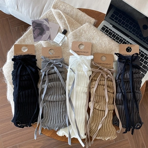 JK style knit leg warmers with ribbons in black, white, grey and khaki on a wooden table