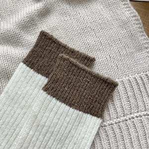 Close-up of thick wool socks with cream body and dark brown ribbed contrast cuffs