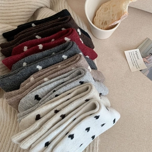 Detail of wool socks with heart patterns in multiple colors on a soft blanket