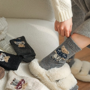 Close-up of winter wool socks with cute bear embroidery and thick knitted texture