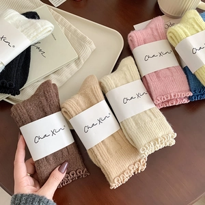 Detail of wool socks with ruffled edges in multiple colors including cream and beige