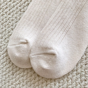 Macro shot of vertical rib knit texture on the toe area of a beige mink velvet sock