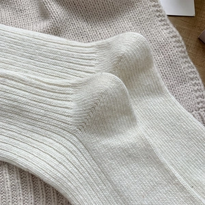 Close-up of white ribbed wool socks showing premium knit texture and elastic cuffs