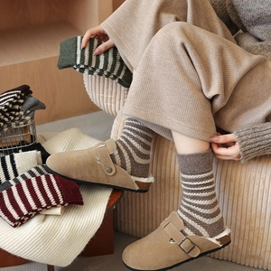 Close-up of thick striped wool socks in retro tones styled with cozy shearling clogs