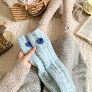 Gros plan détaillé de chaussettes en laine bleu et beige avec cœurs au crochet et torsades