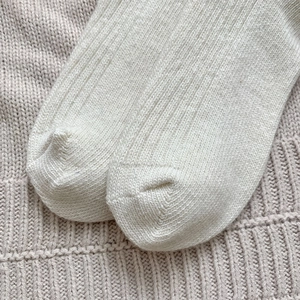 Close-up of cream wool blend ribbed knit socks showing thick warm texture and stitching