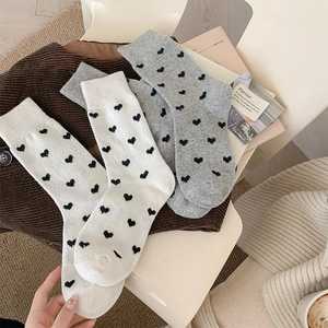 Detailed view of gray and white knitted wool socks with black heart jacquard patterns
