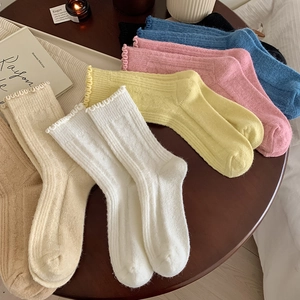 Close-up of colorful ruffled wool socks with knit ribbed texture on a wooden table
