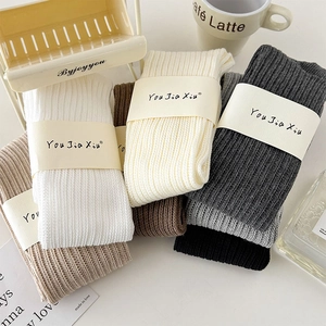 Detail of ribbed knit cotton socks in earthy tones with minimalist paper packaging