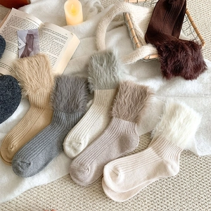 Macro shot of thick knit socks with faux fur trim and ribbed texture in earthy tones