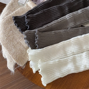 Detailed view of four colors of knitted ribbed leg warmers with elegant lettuce edges