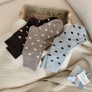 Detailed knit texture of wool crew socks featuring lovely heart patterns in autumn colors