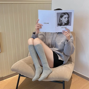 Detail of warm grey ribbed knit high socks on a model in a cozy indoor setting