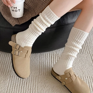 Detail of beige suede Boston clogs paired with white chunky knit ribbed slouch socks