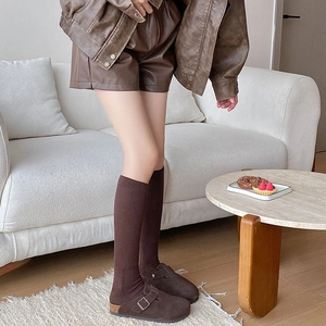 Detail of dark brown suede mule shoes paired with thick winter knit calf socks
