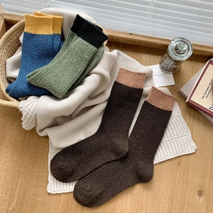 Close-up of thick ribbed wool socks in color-block designs on a cozy wooden desk