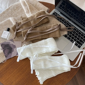 Detail of knitted leg warmers with lace-up drawstrings in brown and white tones