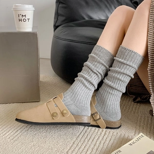 Detail of beige suede clogs with adjustable buckles and grey ribbed knit crew socks