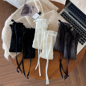 Detail of ribbed knit leg warmers with bows in black, white and grey colors