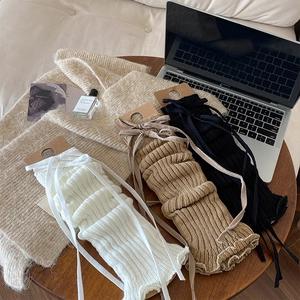 Detailed knit texture of JK-style leg warmers with ribbons in white, khaki and black