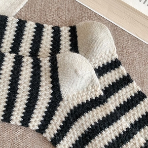 Macro detail of thick striped wool socks showing reinforced heel and warm knitted texture