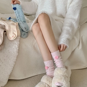 Détail de chaussettes en laine avec cœur au crochet en rose pastel, bleu et crème