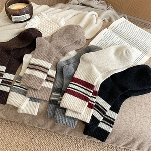 Flat lay of striped wool crew socks in earthy tones on a cozy knitted blanket