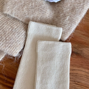 Detailed macro shot of warm off-white knit texture and ribbed cuff on thick calf socks