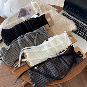 Detailed knit texture of cross-strapped leg warmers in black, grey, white, and dark grey