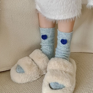 Gros plan sur des chaussettes en laine bleu clair avec cœur 3D et chaussons moelleux