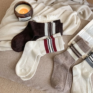 Flat lay of vintage striped wool socks in earth tones with cozy home accessories
