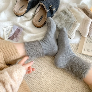 Close-up of thick gray knit socks with plush faux fur trim in a cozy home setting