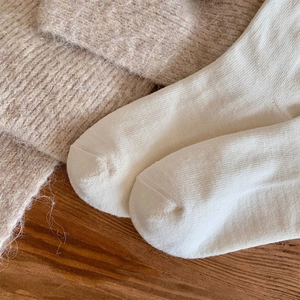 Detailed close-up of white knitted knee-high socks showing smooth toe seam and soft texture
