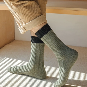 Mens thick wool blend crew socks in dark green with black ribbed cuffs and warm texture