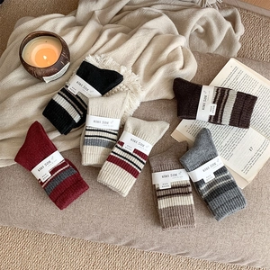 Detailed view of six thick wool knit socks in warm colors on a soft fleece blanket