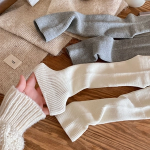 Detail view of thick cable knit texture in cream and grey winter leg warmers