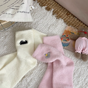 Détail de chaussettes d'hiver chaudes avec broderies chat et koala sur tissu peluche