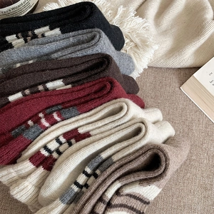 Close-up of thick knitted wool socks in earthy tones with striped cuffs for winter