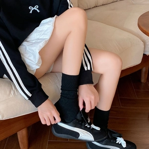 Detail of classic black sports sneakers with white curved stripes and knit crew socks