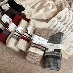 Flat lay of colorful striped wool socks on a cozy knit blanket with a vintage book