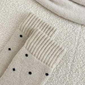 Close-up of beige wool socks with black polka dots and ribbed cuffs for winter warmth