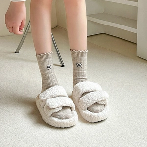 Close-up of wool socks with black bow embroidery and delicate ruffle edge detail