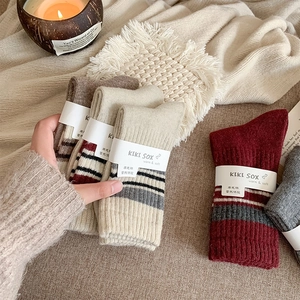 Close-up of thick striped wool socks with paper bands on a cozy beige knit blanket